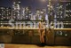 A naked woman standing in front of a city skyline at night.