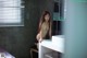 A naked woman sitting on a stool in a bathroom.