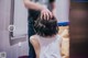 A woman sitting on a toilet with her back to the camera.