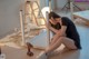 A woman sitting on the floor with a drill in her hand.