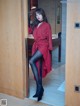 A woman in a red coat and black tights standing in a doorway.