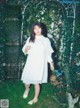 A woman in a white dress standing in the grass.