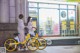 A couple of people standing next to a yellow bike.