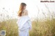 A woman in a white dress standing in tall grass.