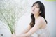 A woman in a white dress holding a bunch of flowers.