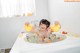 A woman in a bathtub playing with rubber ducks.